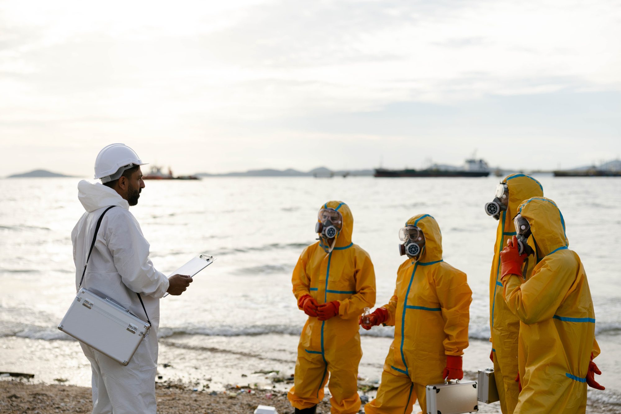 An emergency response team in hazmat suits receiving a briefing during a drill
